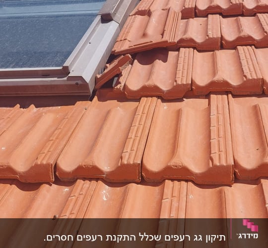 רעפים כתומים עם חלון גג על רקע שמיים כחולים